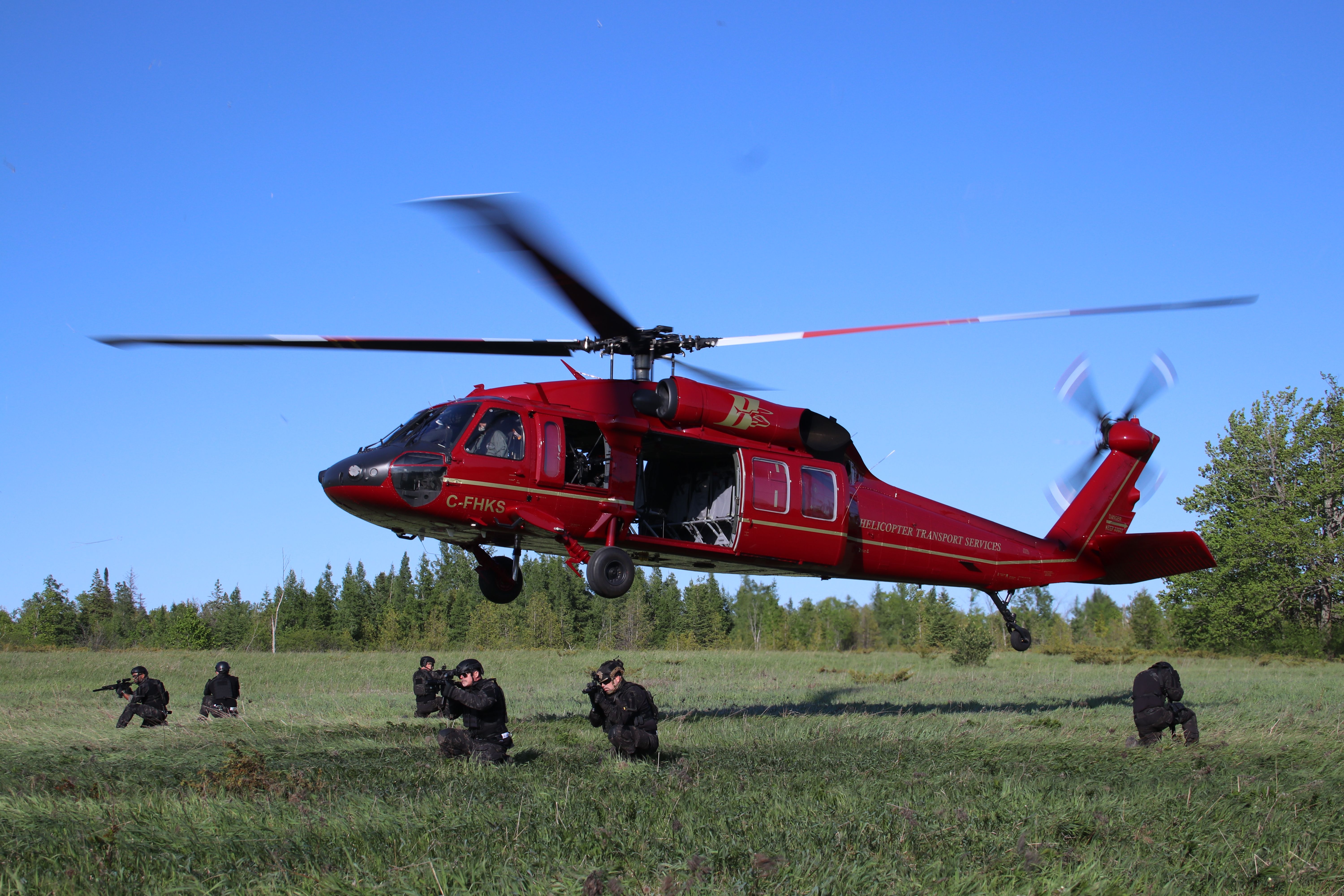 Black Hawk hovering low as a team crosses the field beneath it