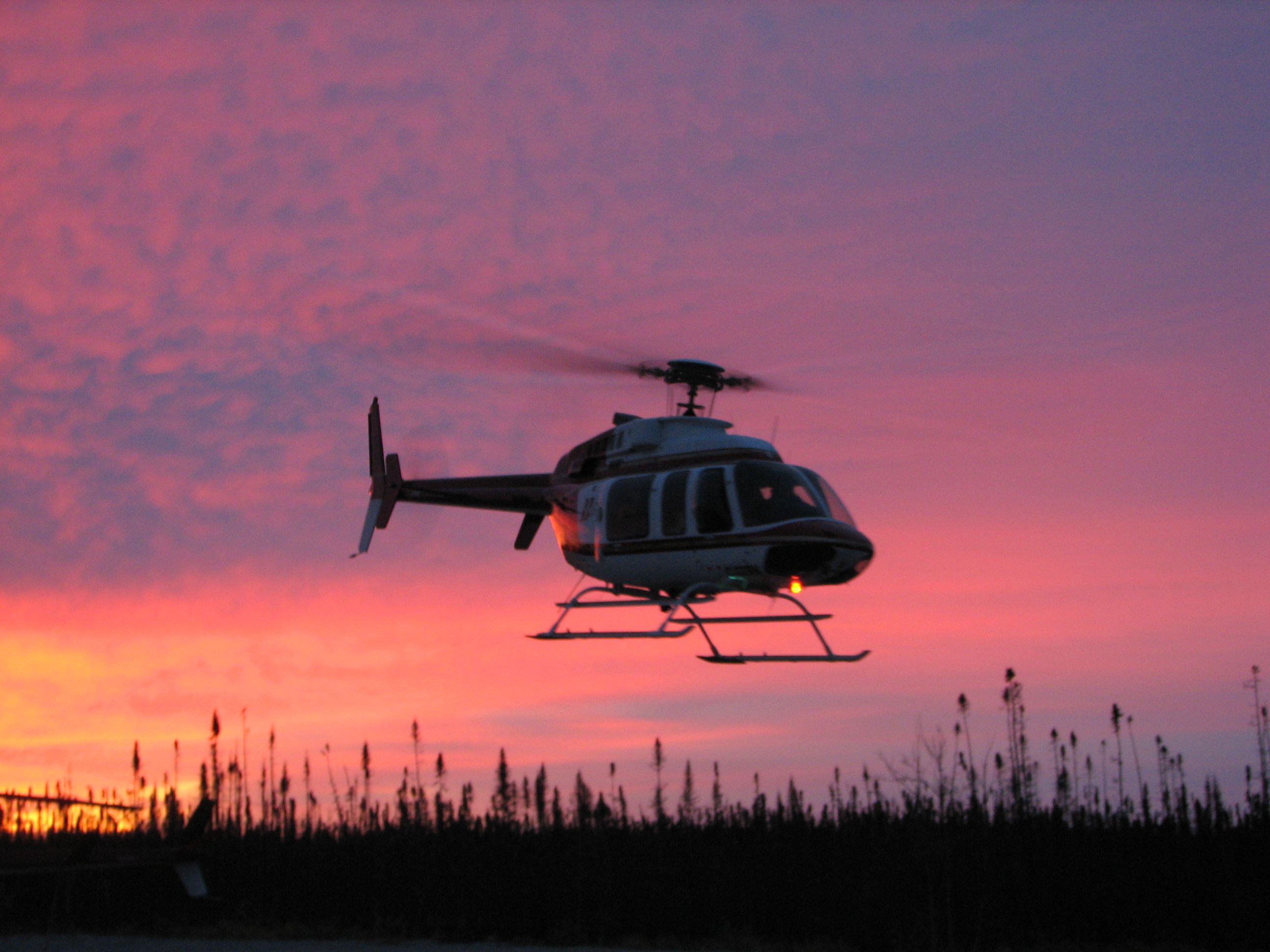 Bell 407 silhouetted against a red sunset