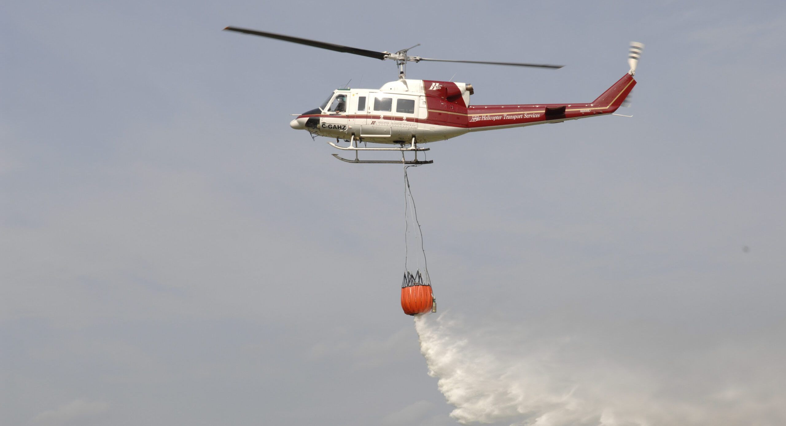 Bell 212 releasing water from a bucket on a long line