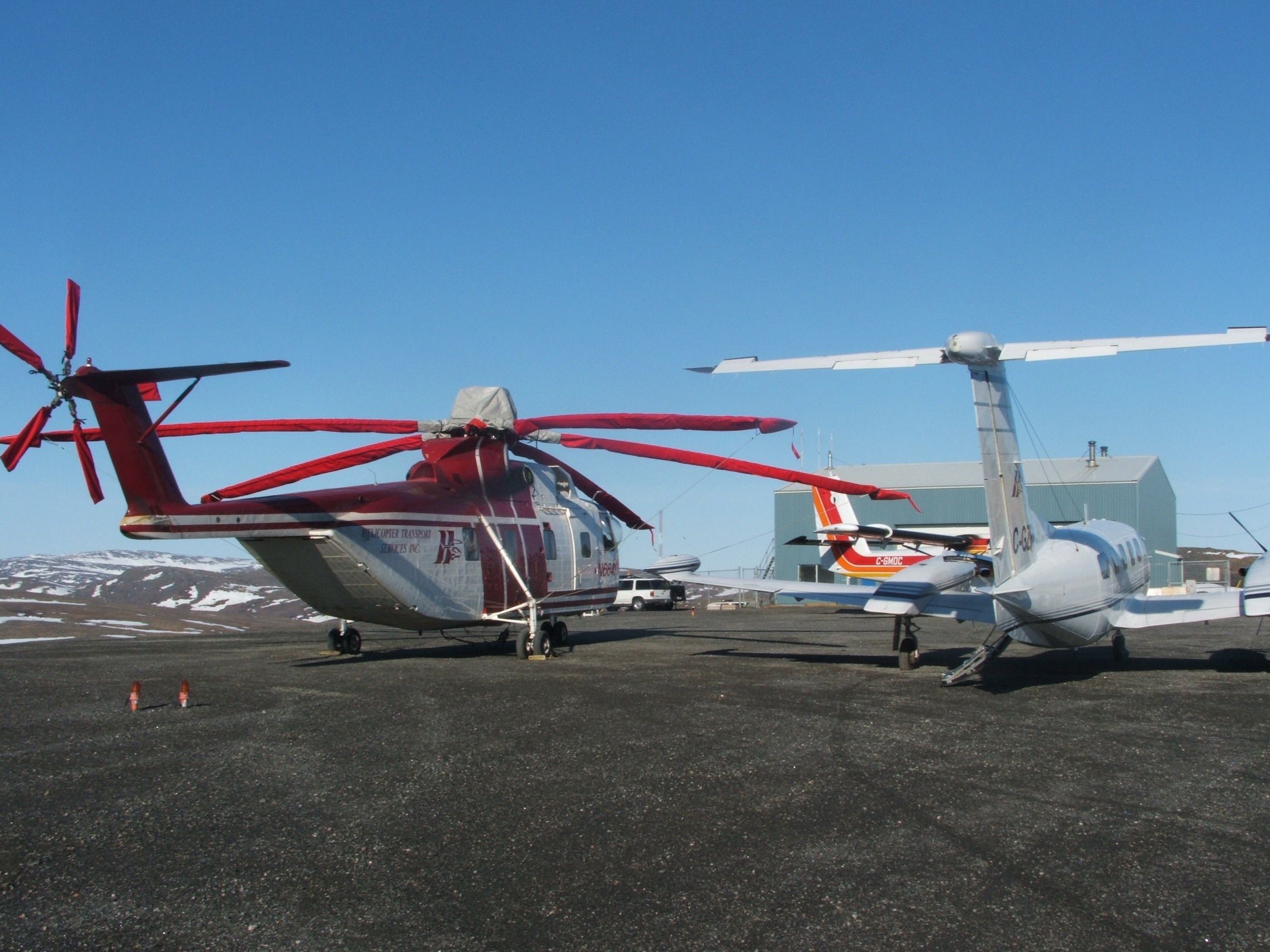 Skycrane and a light helicopter on a gravel ramp