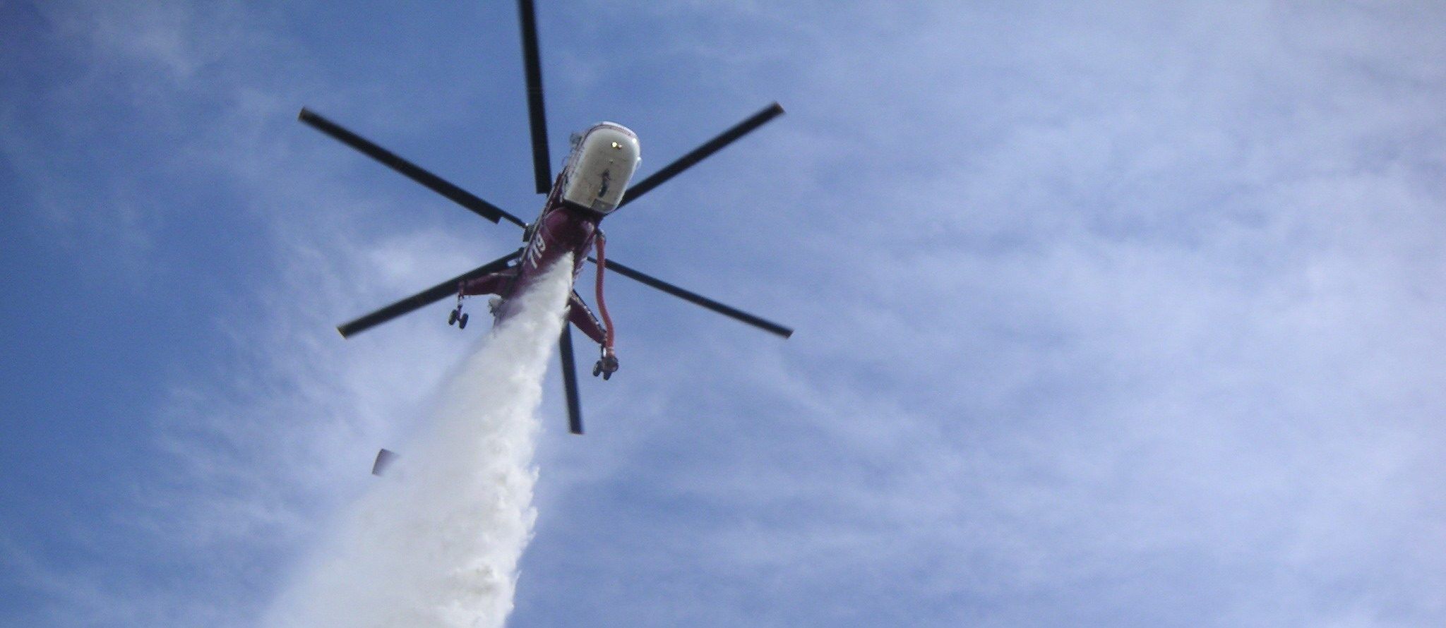 Skycrane overhead releasing a stream of water