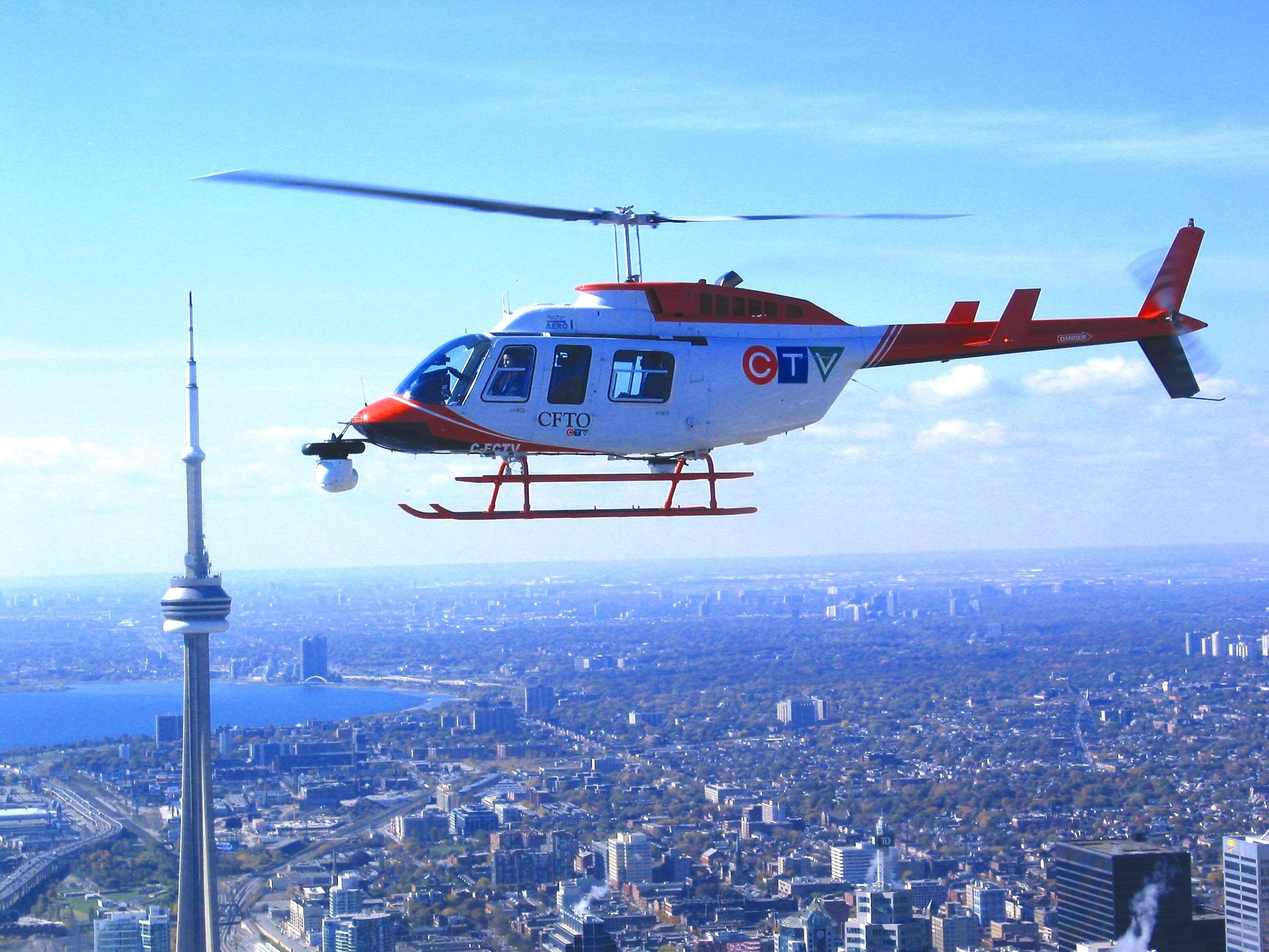 Bell 206 in news livery flying over Toronto beside the CN Tower