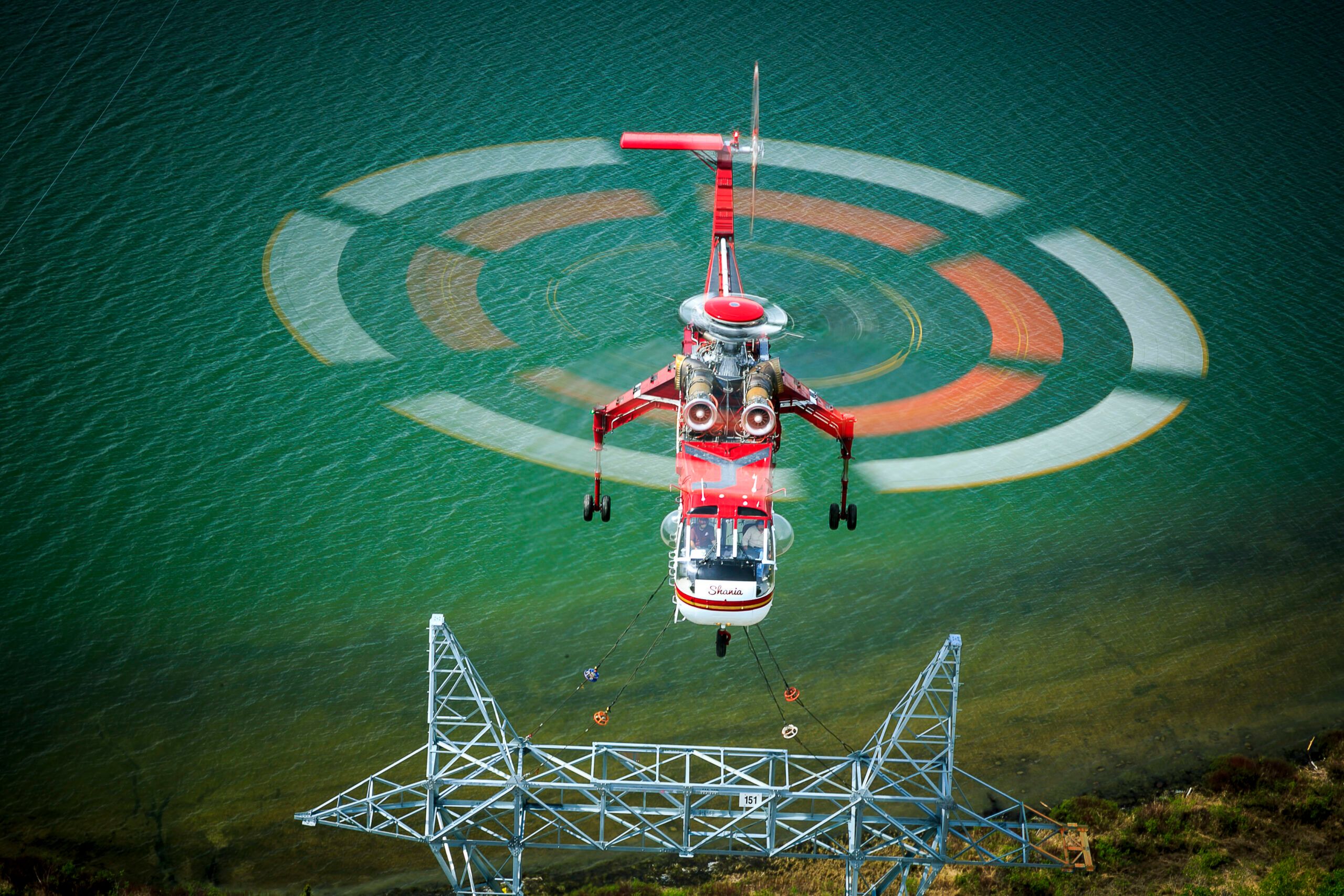 Top-down view of a Skycrane setting a transmission tower section over a green helipad target