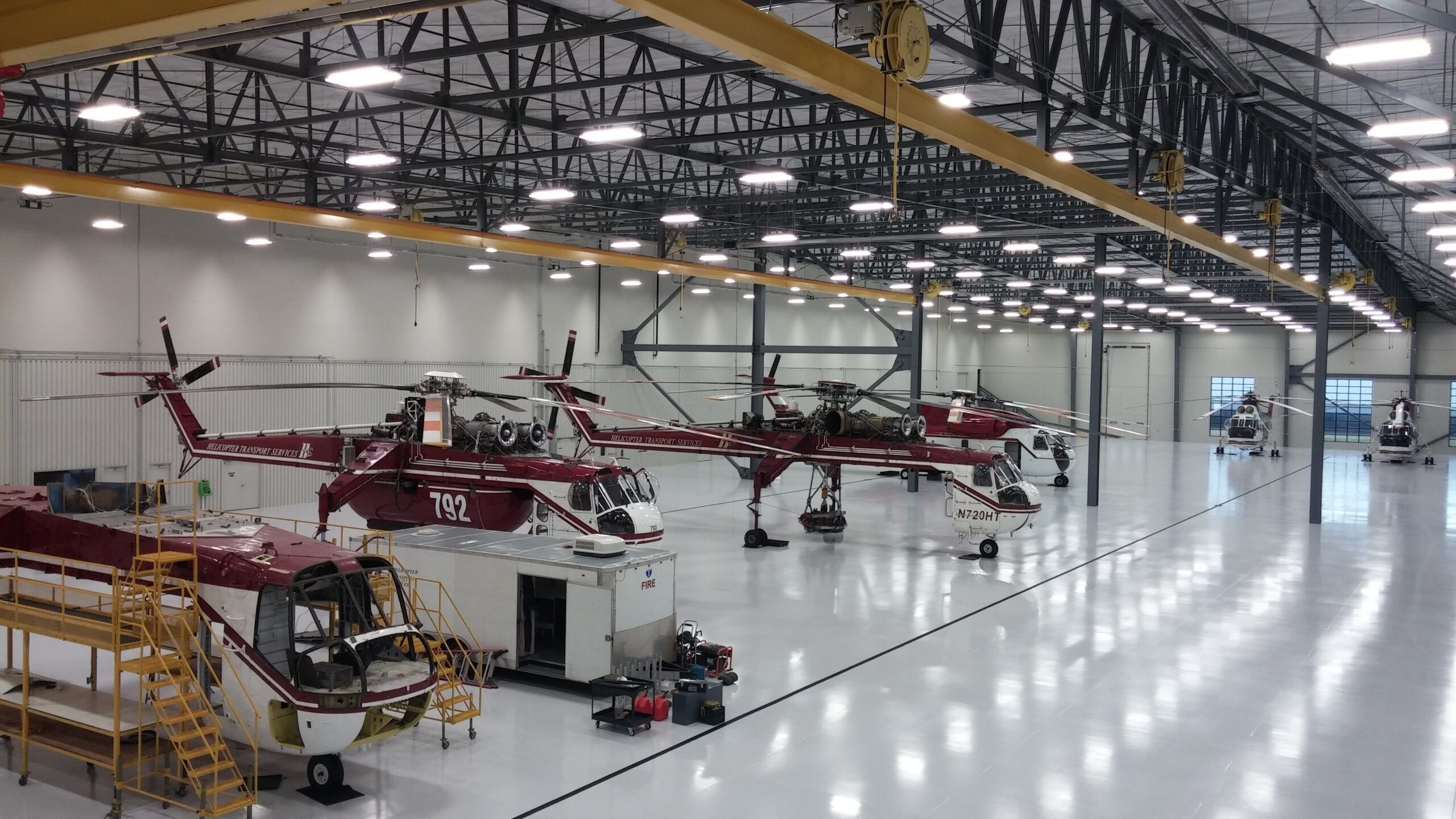 Inside the Aurora hangar: Skycranes and an S-61 under bright lights on a polished floor