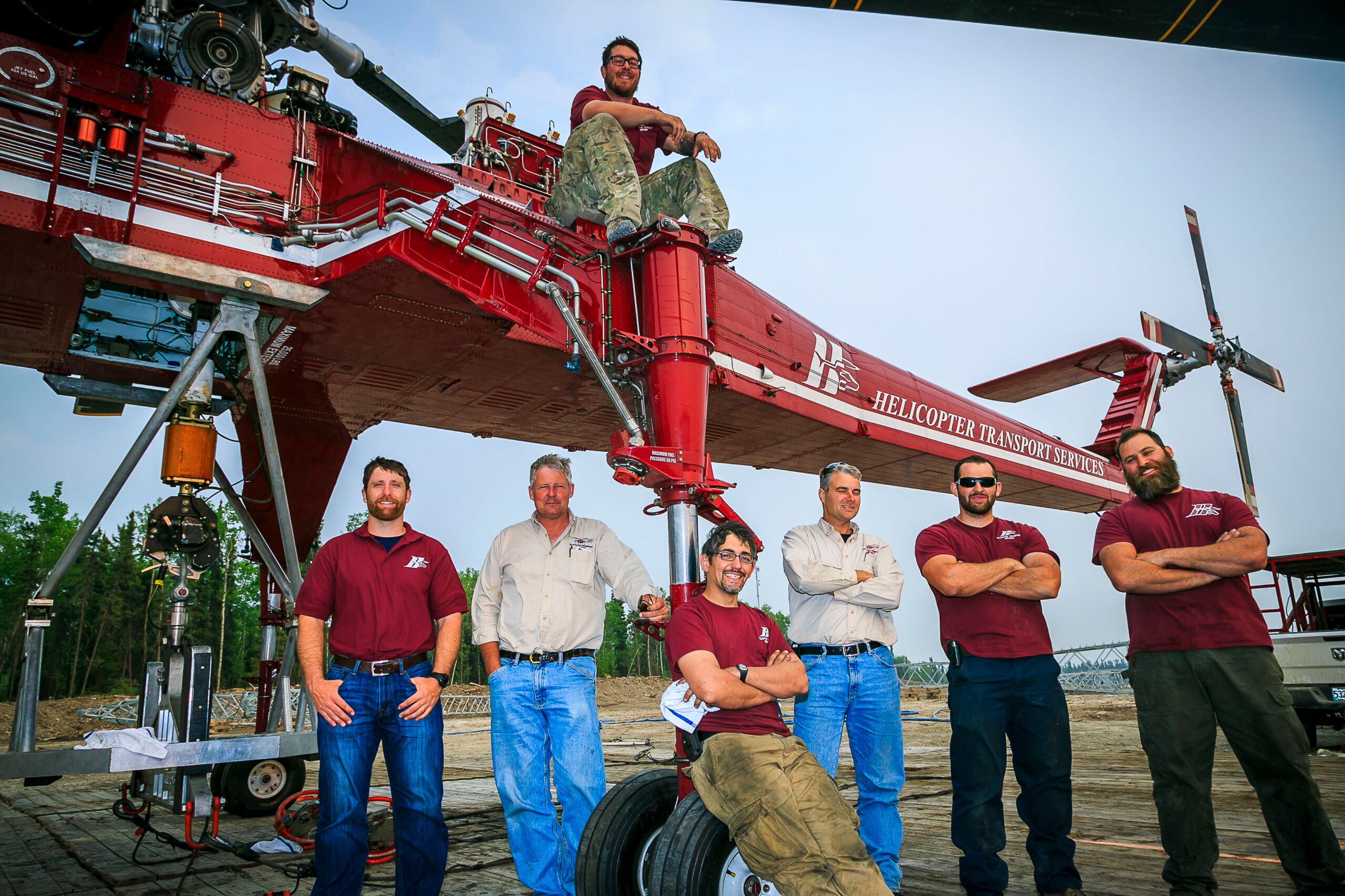 Seven HTS crew members in company shirts in front of a Skycrane on a job site