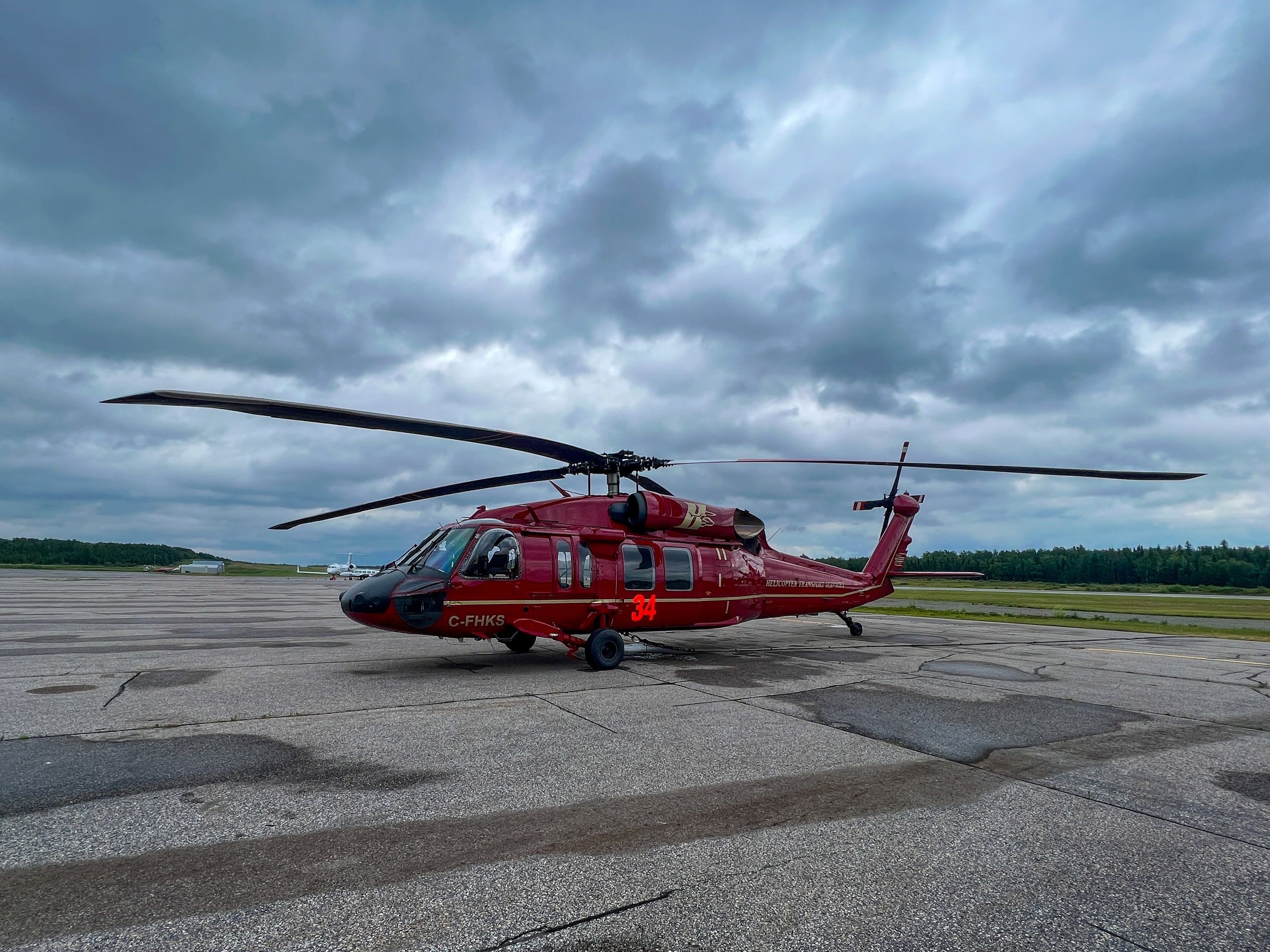 HTS Black Hawk in red livery parked on a ramp under a heavy, cloudy sky