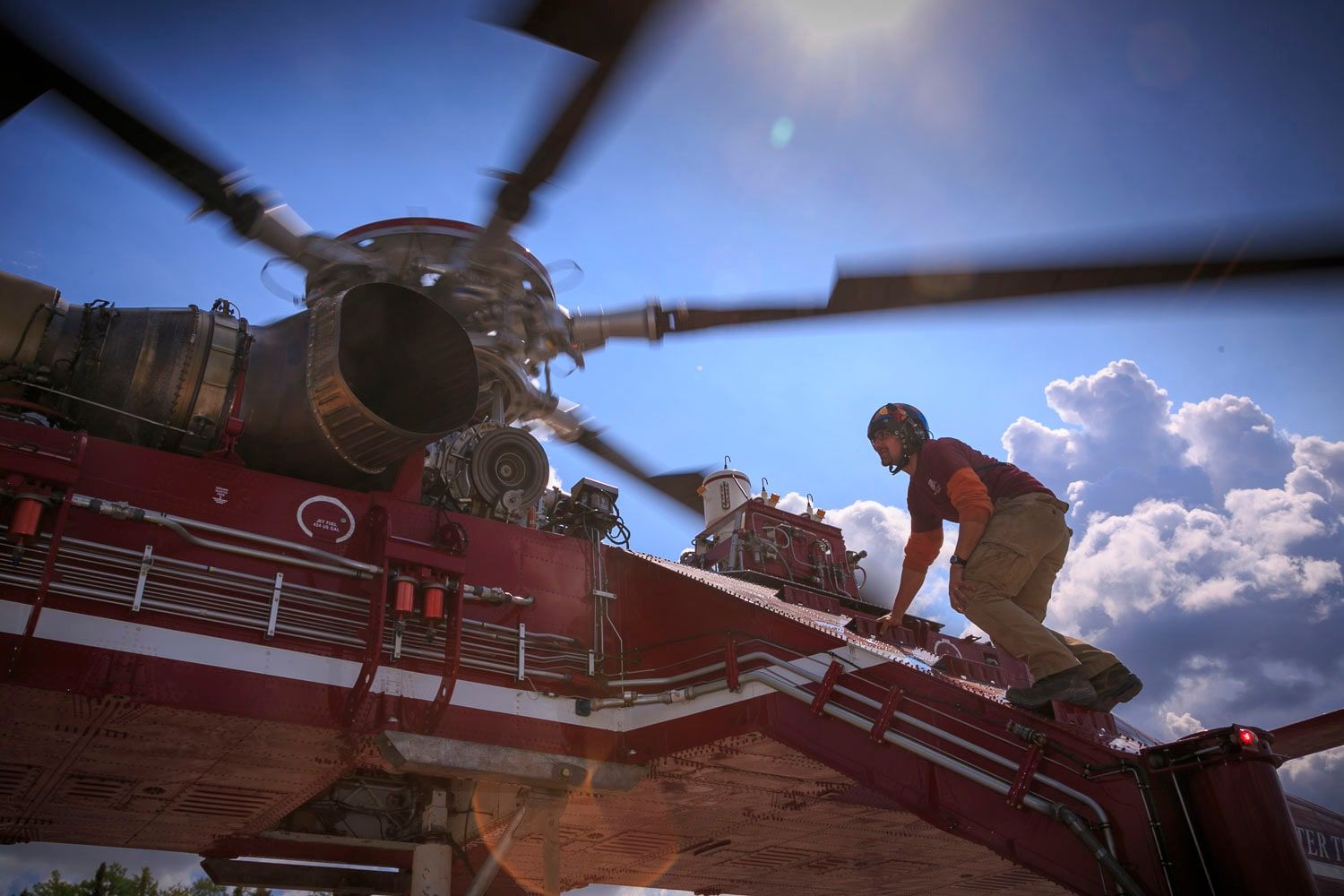 Technician kneeling on top of a Skycrane beside the rotor mast